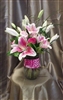 Tall pink bouquet with Stargazer lilies, pink roses, lily grass, and greenery in a clear cylinder vase wrapped with a pink ribbon.