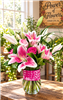 Pink Stargazer lily and rose bouquet in a clear glass vase with decorative pink ribbon
