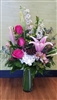 Fuchsia Lily and Rose bouquet with stargazer lilies, hot pink roses, pink larkspur, white hydrangea, alstroemeria, eucalyptus, and lotus pod in a clear cylinder vase