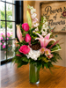 Fuchsia Lily and Rose bouquet with stargazer lilies, hot pink roses, pink larkspur, white hydrangea, alstroemeria, eucalyptus, and lotus pod in a clear cylinder vase