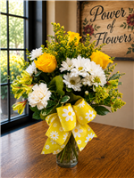 Bouquet with white daisies, yellow roses, carnations, and greenery finished with a yellow daisy-print bow.