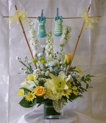 New baby boy bouquet with yellow roses, lilies, white larkspur, carnations, yellow daisies, and baby booties.