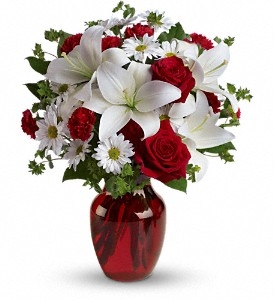 Red and white floral arrangement with roses, Asiatic lilies, mini carnations, and chrysanthemums in a ruby glass vase