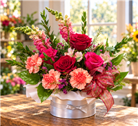 Red roses and pink carnations with greenery in a round hat box arrangement
