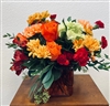 Orange and red bouquet with roses carnations alstroemeria and daisies in a glass vase