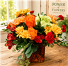 Orange and red bouquet with roses carnations alstroemeria and daisies in a glass vase