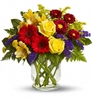 Sunny mixed bouquet with yellow roses, red gerbera-style blooms, purple statice, alstroemeria, and greenery in a clear vase