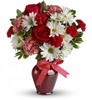 Red, pink, and white bouquet with roses, carnations, and chrysanthemums in a red glass vase