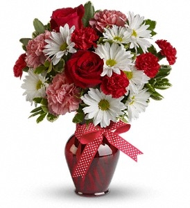 Red, pink, and white bouquet with roses, carnations, and chrysanthemums in a red glass vase