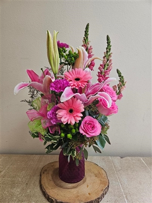 Pink roses and lilies bouquet with snapdragons, gerbera daisies, carnations, and greenery in a clear vase
Bright pink birthday flower arrangement with roses, lilies, and carnations, all-around design.
