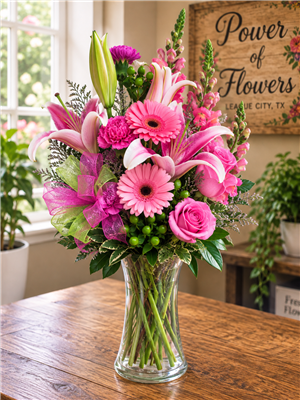 Pink roses and lilies bouquet with snapdragons, gerbera daisies, carnations, and greenery in a clear vase
Bright pink birthday flower arrangement with roses, lilies, and carnations, all-around design.