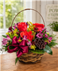 Autumn basket arrangement with orange roses, purple alstroemeria, burgundy button mums, solidago, greenery, and a lotus pod with a berry bow.