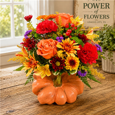 Autumn bouquet with orange roses, red carnations, bronze poms, alstroemeria, and berries arranged in a ceramic pumpkin container.