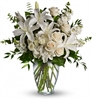 Tall all-white vase arrangement with hydrangea, roses, spray roses, stock, and eucalyptus in a clear vase.