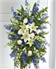 Blue and white standing sympathy tribute with lilies, roses, delphinium, and snapdragons
