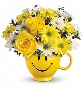 Smiley face mug bouquet with yellow roses, yellow daisies, white daisies, and greenery.