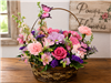 Basket in Blooms arrangement with hot pink spray roses, light pink alstroemeria, snapdragons, mini carnations, waxflower, purple matsumoto asters, Monte Cassino asters, statice, and pittosporum with two butterflies in a wicker basket